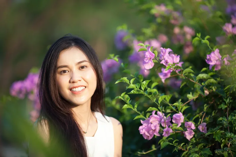Woman smiling near purple flowers in garden setting outdoors
