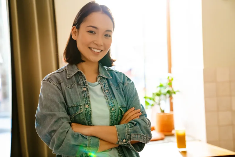 Woman in denim shirt smiling with natural indoor lighting and confident pose