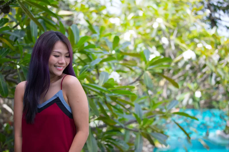 Smiling woman in natural garden setting with tropical background