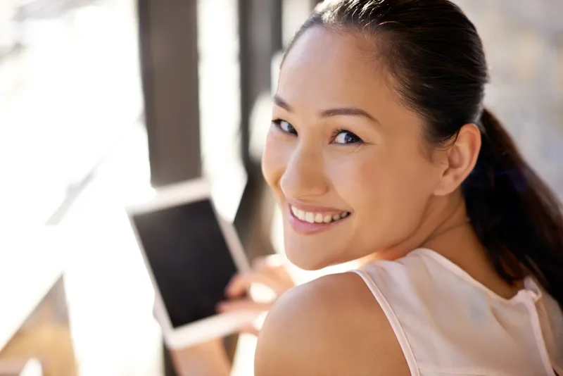 Happy woman holding a digital tablet in home environment