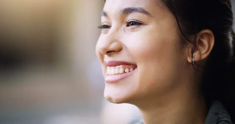 Woman smiling joyfully in natural light, reflecting family happiness and togetherness
