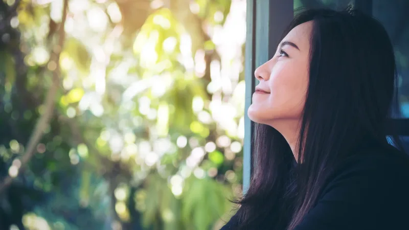 Woman gazing peacefully in nature, contemplating the meaningful journey ahead