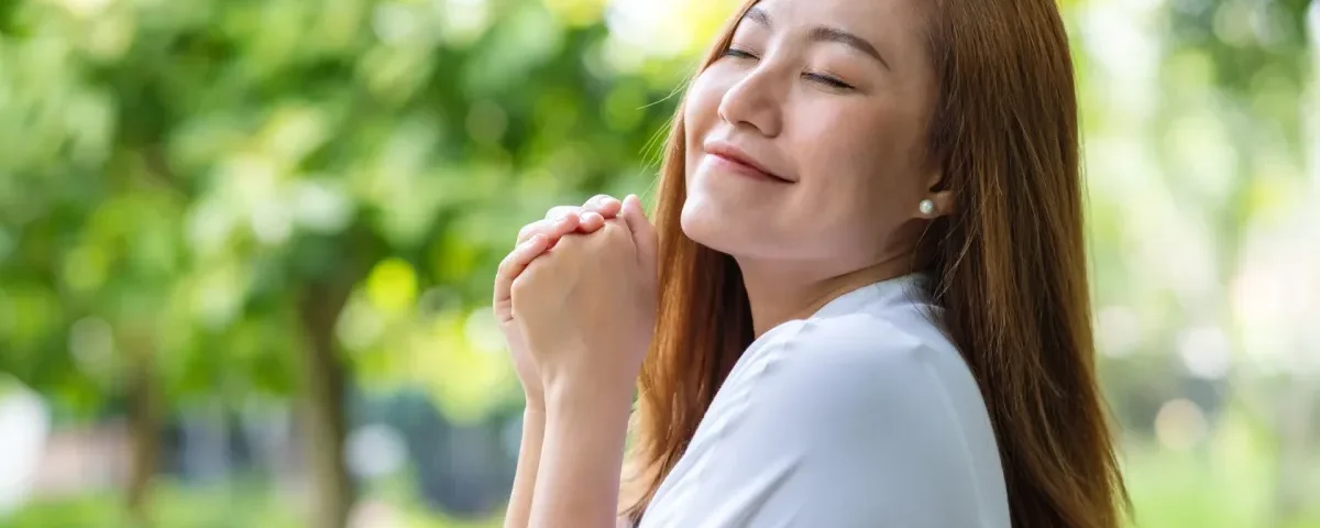 Young woman with eyes closed in peaceful outdoor setting, serene expression