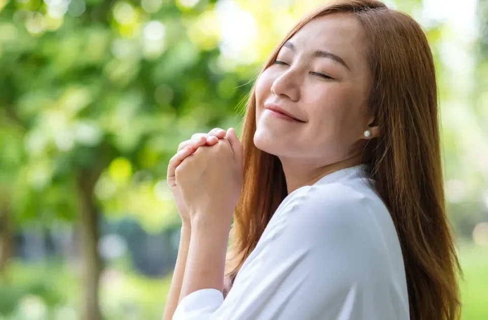 Young woman with eyes closed in peaceful outdoor setting, serene expression