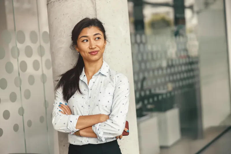 Woman office worker standing confidently in urban setting, showing assured presence