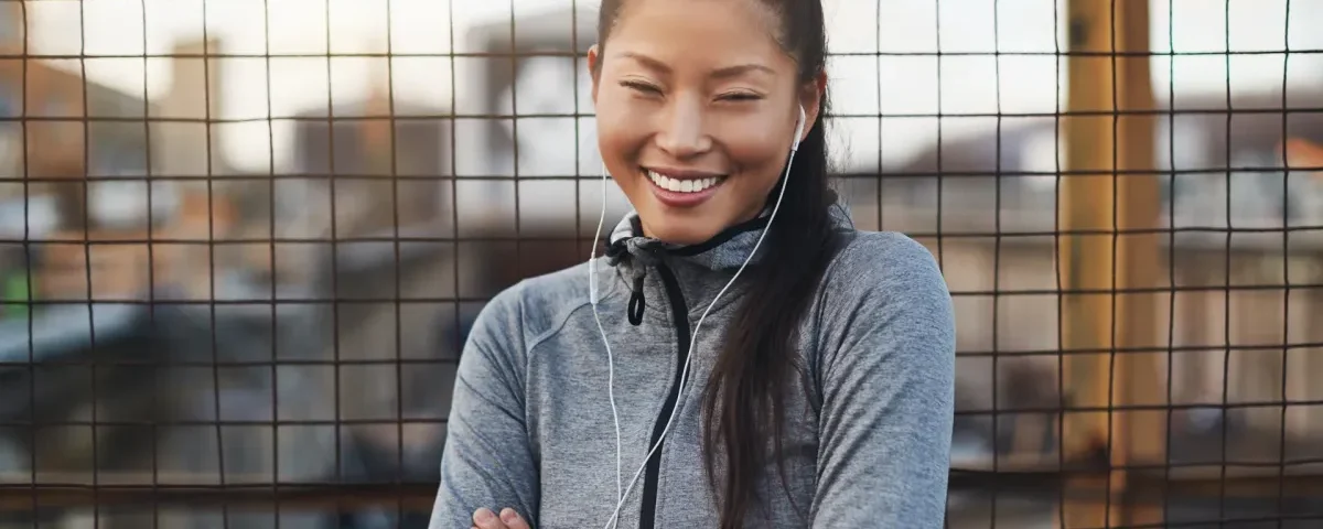 Woman in athletic wear smiling confidently outdoors in urban setting
