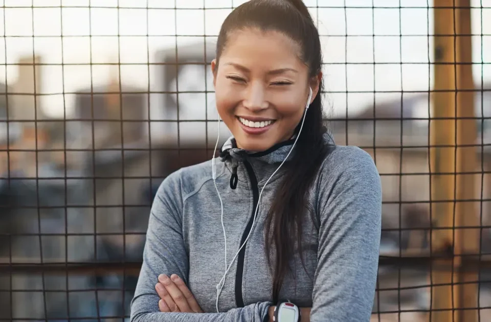 Woman in athletic wear smiling confidently outdoors in urban setting
