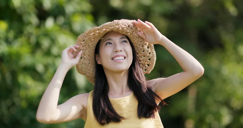 Woman in straw hat enjoying sunlight in outdoor natural setting