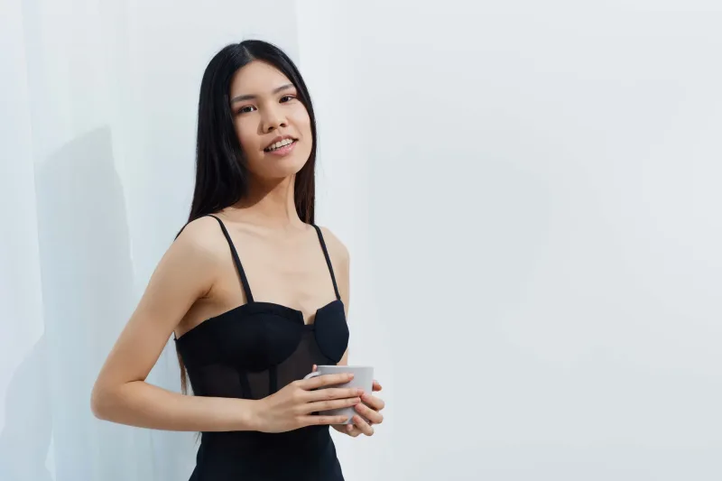 Woman holding coffee cup indoors with confident, elegant demeanor