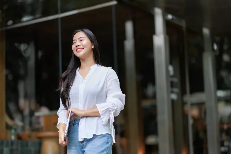 Professional woman holding laptop while walking in urban environment