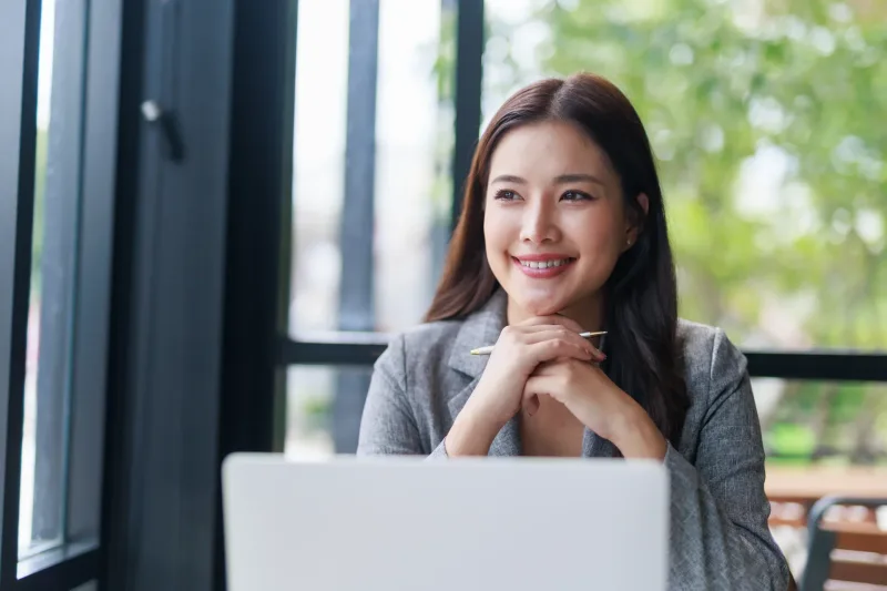 Businesswoman in workspace looking away thoughtfully while working