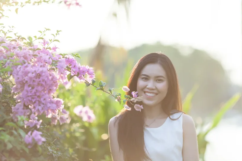 Woman smiling outdoors among flowers in natural setting