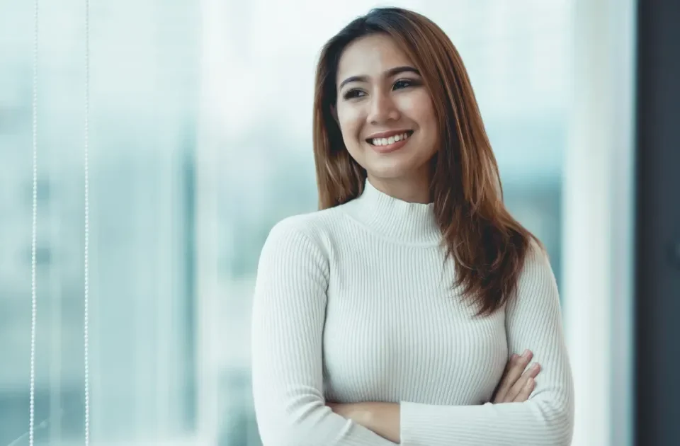 Woman in turtleneck smiling confidently near window