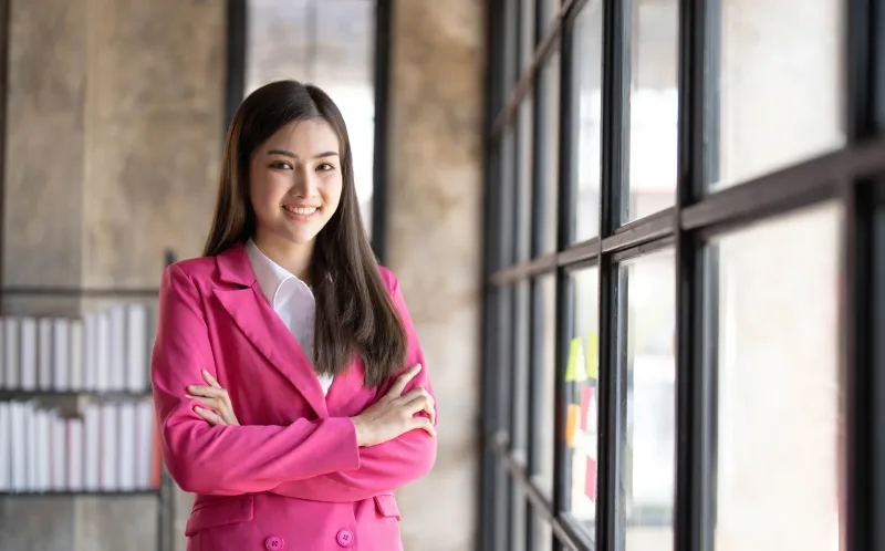 Professional woman in pink jacket at modern office setting