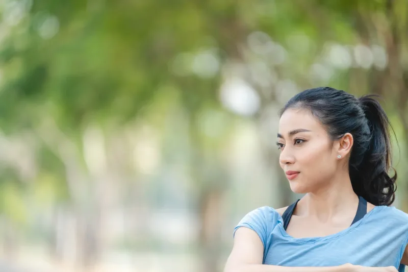 Woman in thoughtful profile view within peaceful natural surroundings