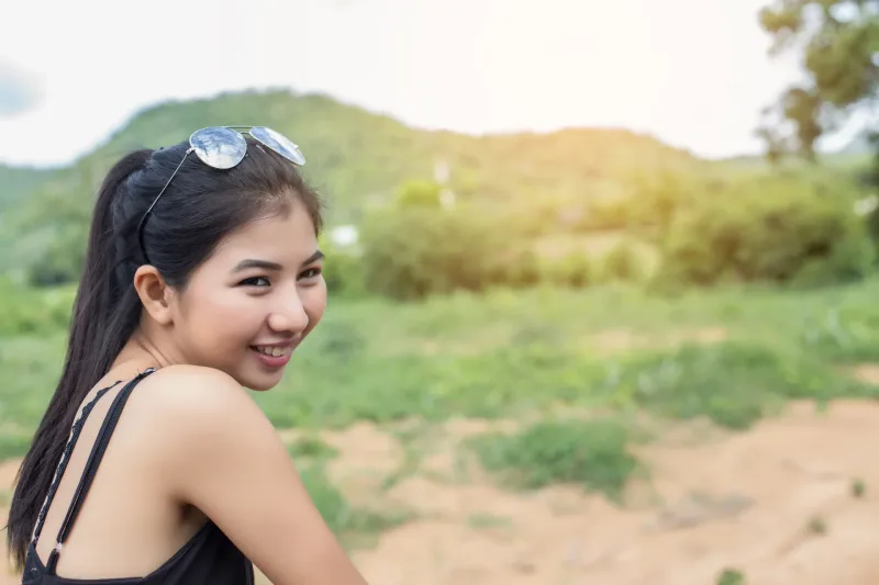 Woman in nature setting with sunglasses and warm smile
