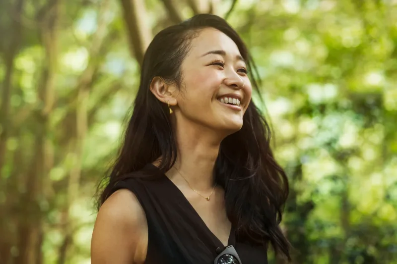 Woman smiling warmly surrounded by natural greenery and foliage