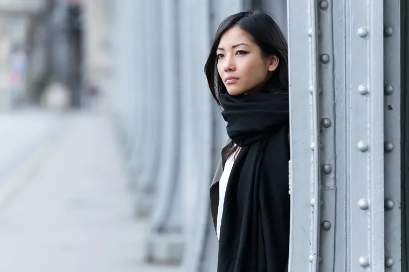 Asian woman with serious, contemplative expression looking to the side