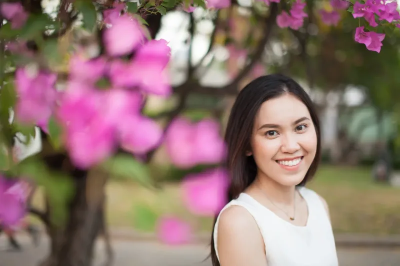 Woman portrait smiling outdoors with pink flowers