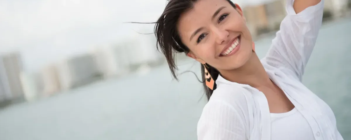 Woman in white shirt smiling confidently at waterfront