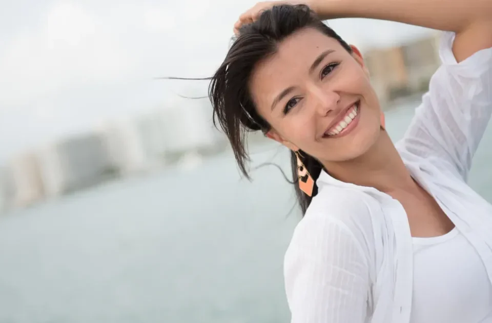 Woman in white shirt smiling confidently at waterfront