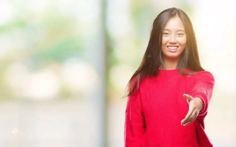 Woman in red sweater extending welcoming gesture with friendly expression