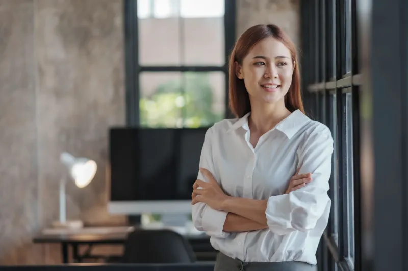 Woman standing confidently near office window with professional composure