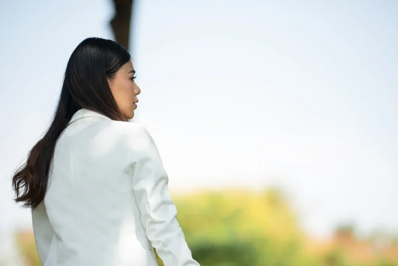 Woman in white blazer shown in profile outdoors in peaceful setting