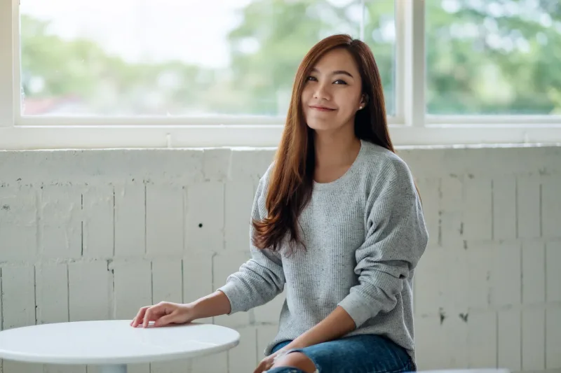 Woman with contemplative smile near natural light, symbolizing thoughtful reflection on relationship progress