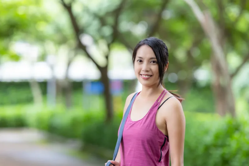 Woman smiling outdoors in natural setting with genuine warmth
