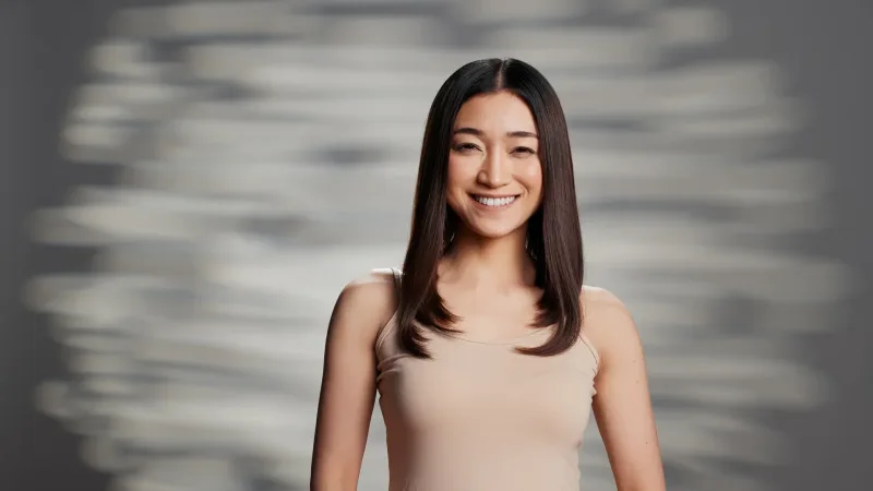 Woman smiling confidently against neutral background, approachable expression