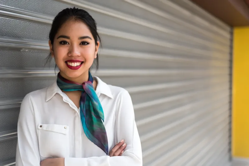 Woman in business casual attire smiling with arms crossed, poised demeanor