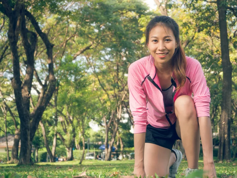 Woman smiling outdoors in park setting, athletic and assured posture