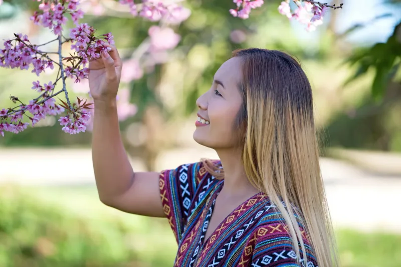 Woman surrounded by spring blossoms, joyful expression amid flowers