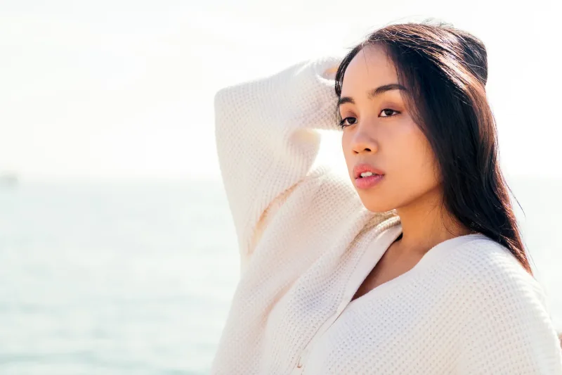 Woman by ocean in serene setting, conveying calm, genuine presence