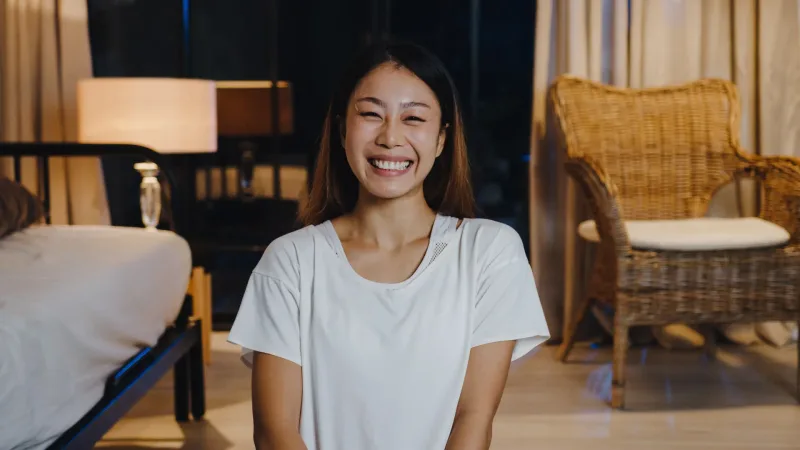 Woman smiling warmly in an indoor setting, conveying comfort and approachability