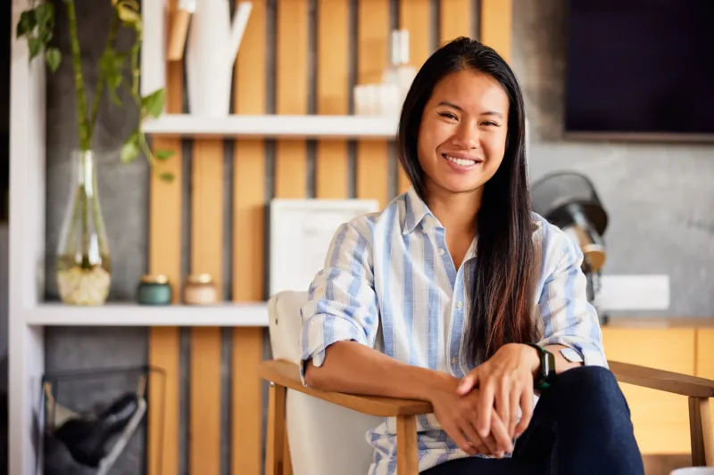 Woman seated indoors in striped shirt, smiling warmly