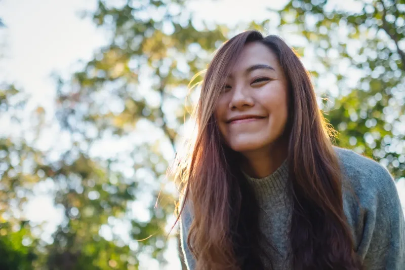 Woman standing outdoors in golden hour light, calm and thoughtful