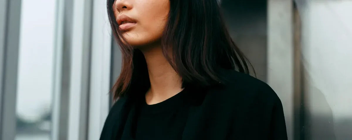 Filipina smiling thoughtfully by a window, reflecting composed confidence and emotional sincerity