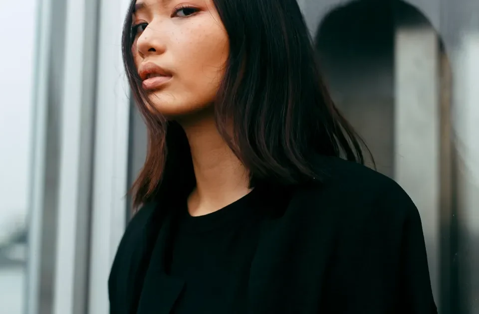 Filipina smiling thoughtfully by a window, reflecting composed confidence and emotional sincerity