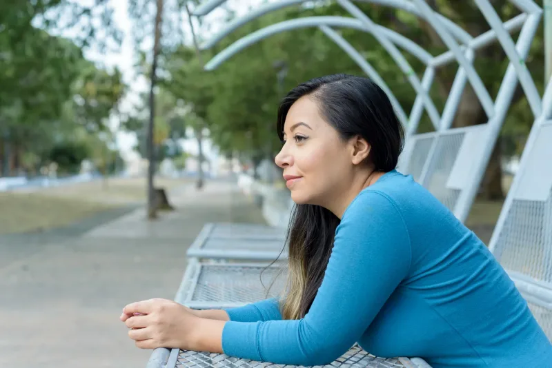 Woman seated peacefully outdoors, contemplative expression