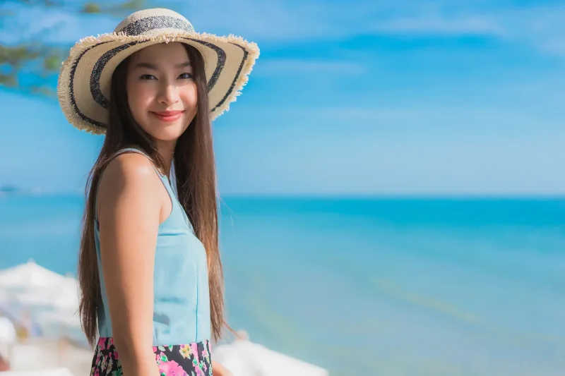 Woman relaxing by ocean with warm smile and engaged presence