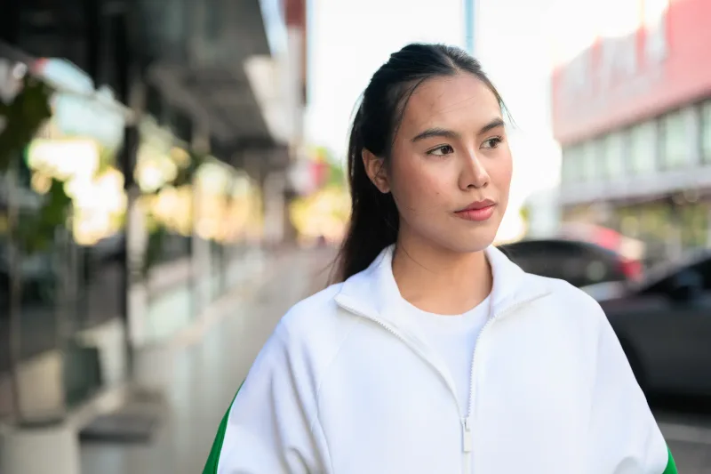 Woman in casual jacket standing outside with contemplative expression