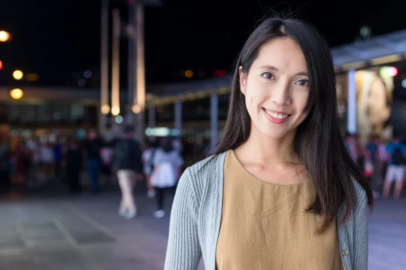 Woman smiling warmly in urban nighttime setting with city lights