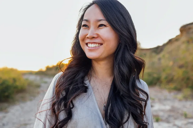 Woman smiling outdoors at sunset in relaxed natural setting