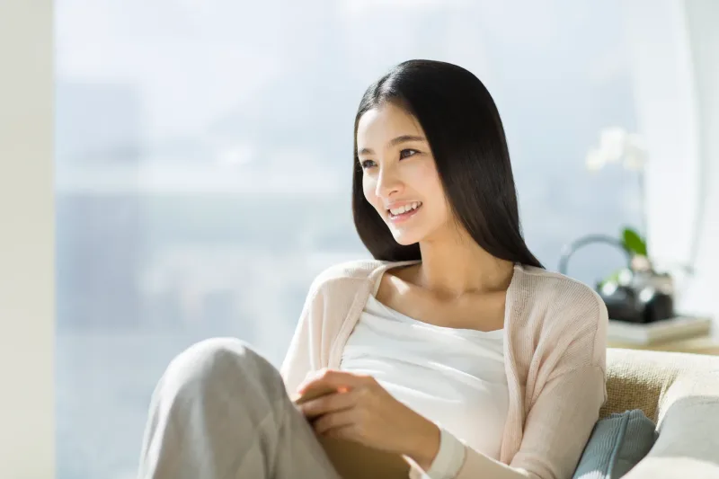 Woman relaxing comfortably indoors with natural light, content and at ease
