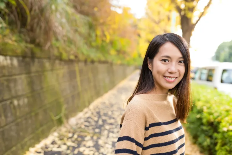 Woman smiling outdoors in autumn setting