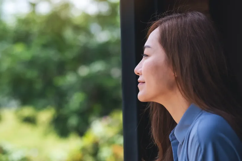 Woman in profile gazing thoughtfully out window