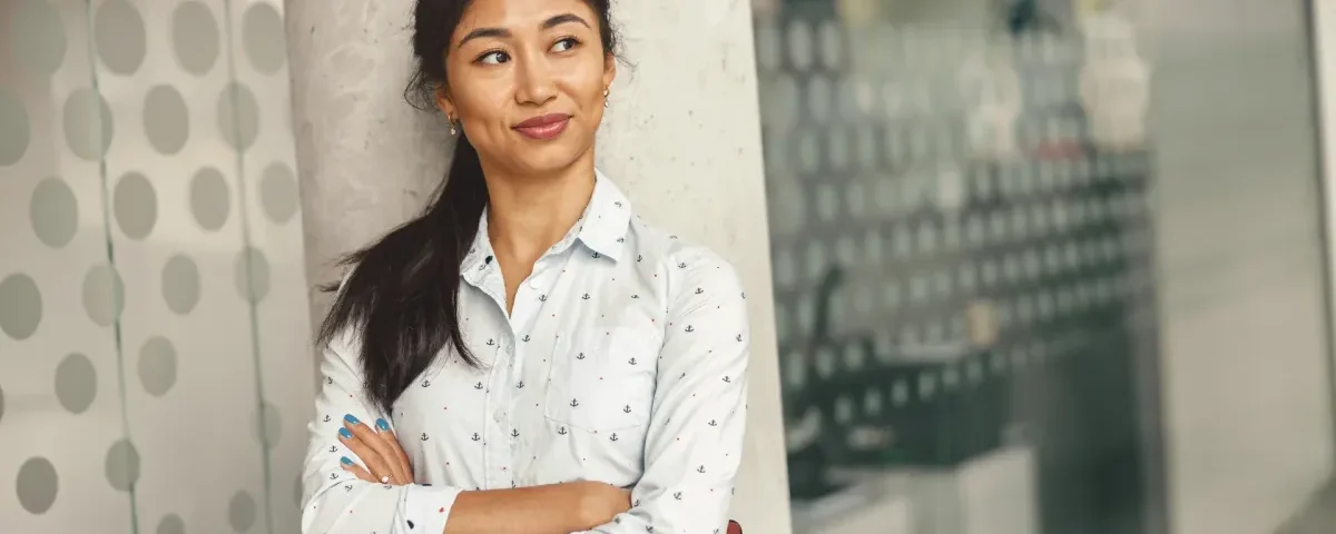 Confident Filipino woman in casual grey shirt smiling outdoors.