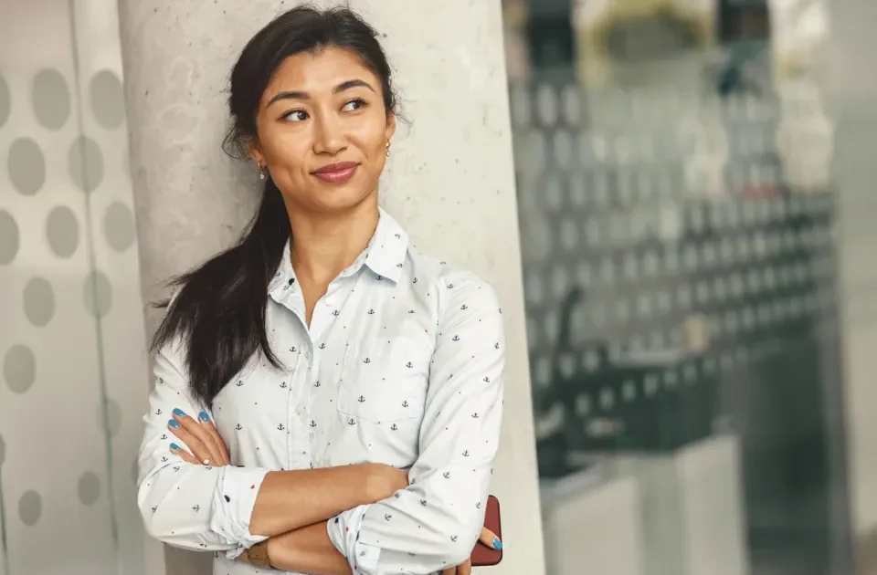 Confident Filipino woman in casual grey shirt smiling outdoors.